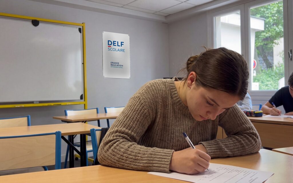 Candidata durante la prova scritta del DELF all'Alliance Française di Salerno, con il poster DELF Scolaire e il logo France Éducation international